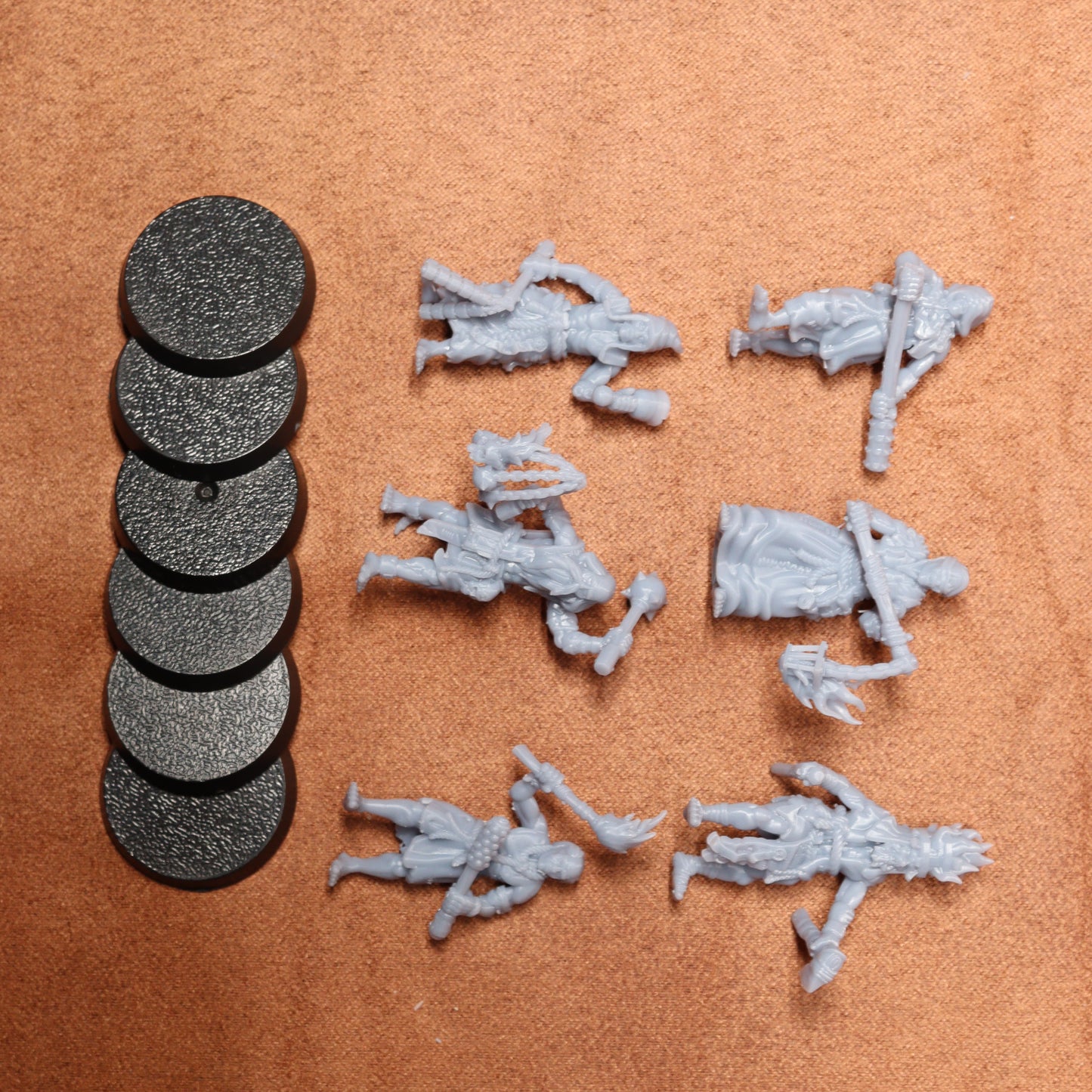 Set of gray miniature figures and round black bases on a brown surface