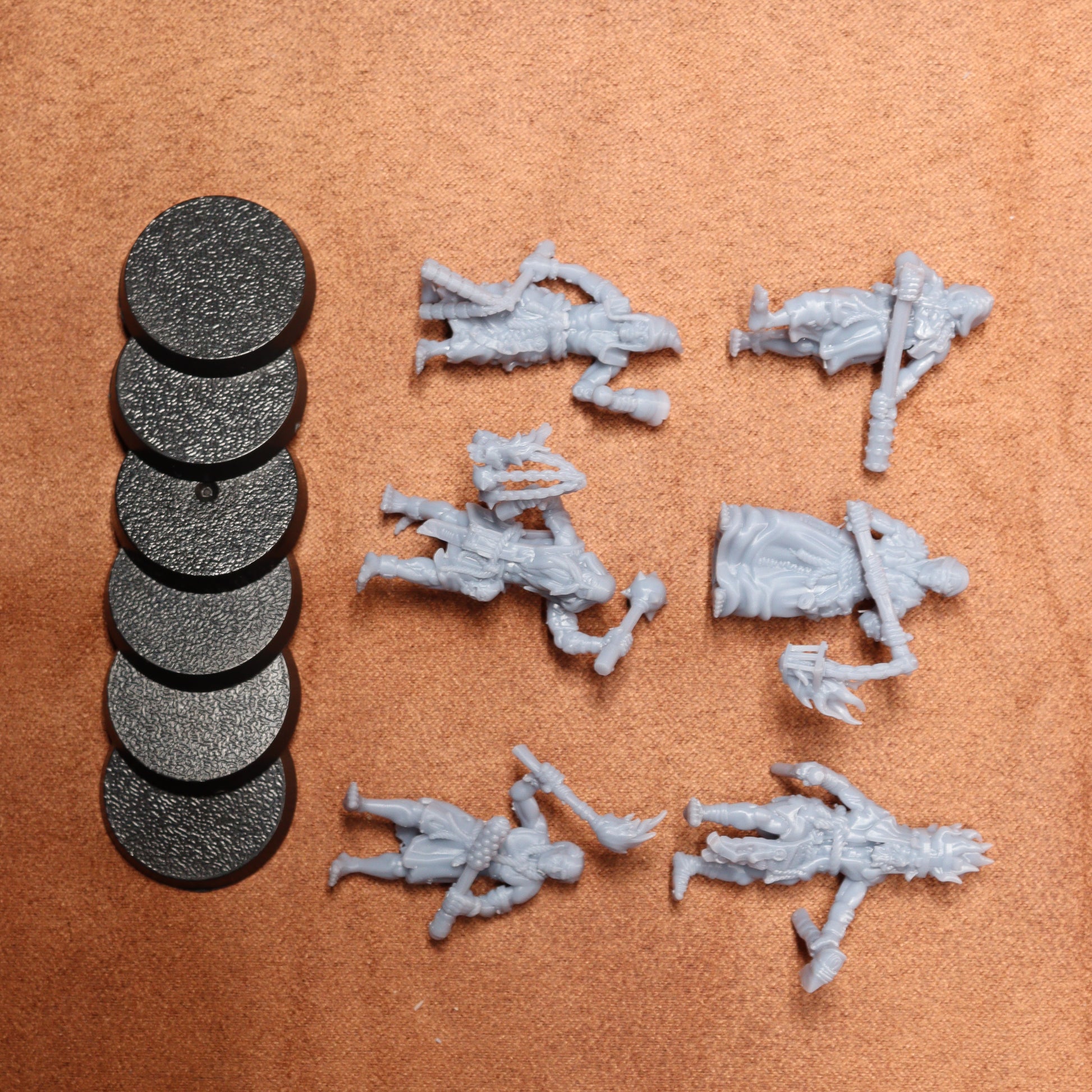 Set of gray miniature figures and round black bases on a brown surface