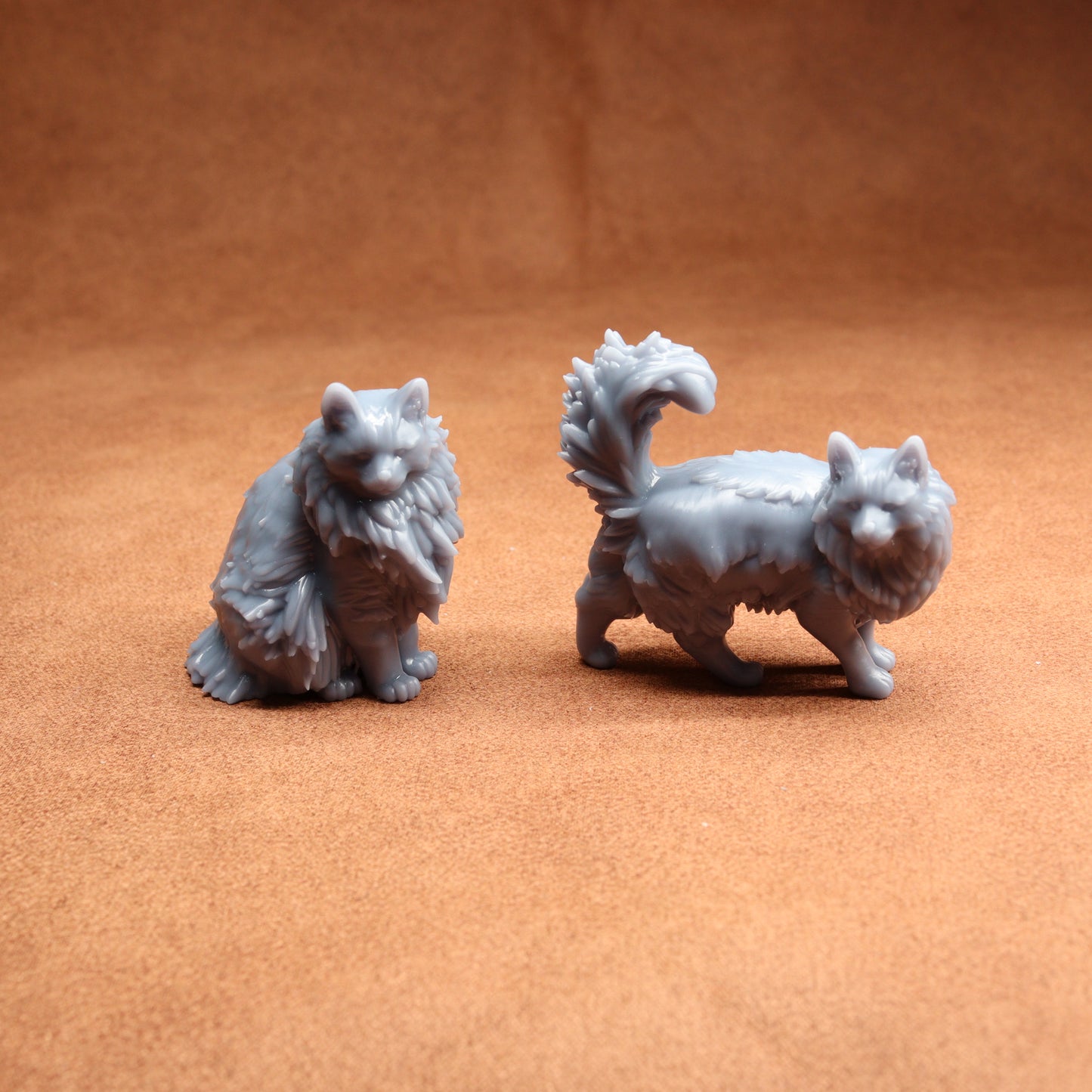 Two gray cat figurines on a brown surface