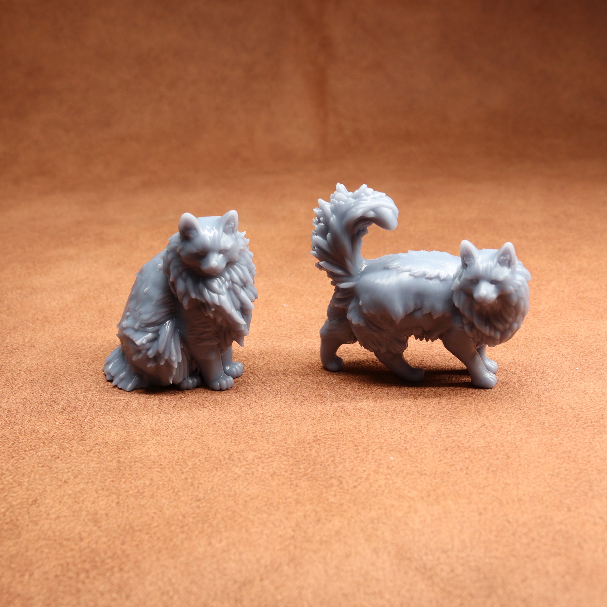 Two gray cat figurines on a brown surface