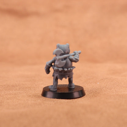 A small unpainted gray fantasy miniature figurine of a warrior holding a mace, standing on a round black base against a warm brown textured background.