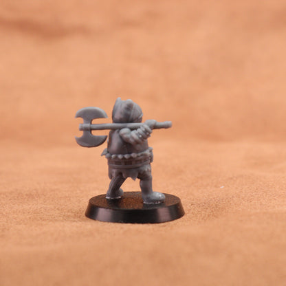 A small unpainted gray fantasy warrior miniature figurine holding a double-headed axe, standing on a round black base against a warm brown textured background.