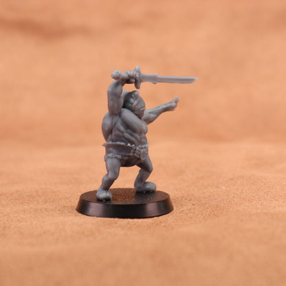 A small unpainted gray fantasy miniature figurine of a barbarian holding a sword, standing on a round black base against a warm brown textured background.