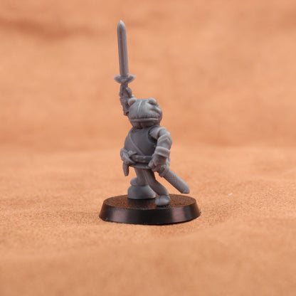 A small unpainted gray fantasy warrior miniature figurine holding a sword aloft, standing on a round black base against a warm sandy beige background.