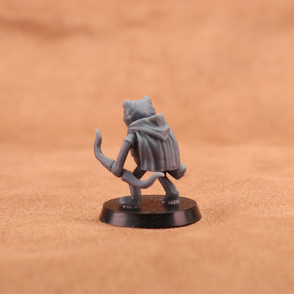 A small gray fantasy miniature figurine of a cat-like character wearing a hooded cloak, standing on a round black base against a warm tan textured background.
