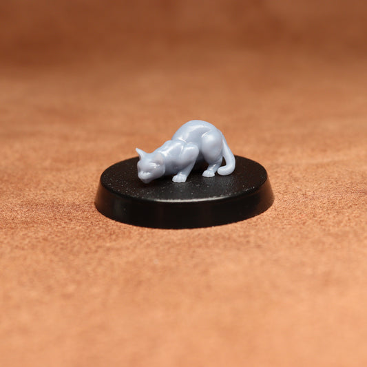 Small white cat figurine on a black round base against a brown background