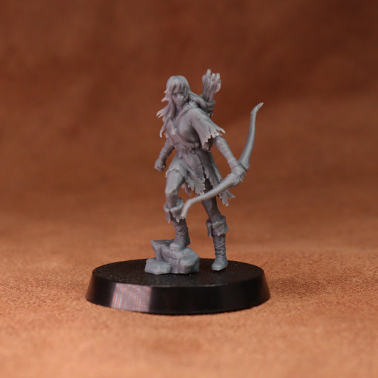 A small unpainted gray fantasy tabletop miniature figurine of a female archer standing on a round black base against a warm brown textured background.