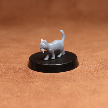 Small gray cat figurine on a black round base against a brown background