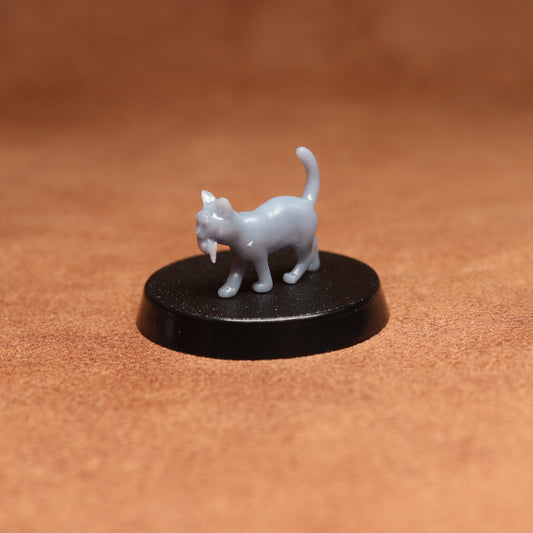 Small gray cat figurine on a black round base against a brown background