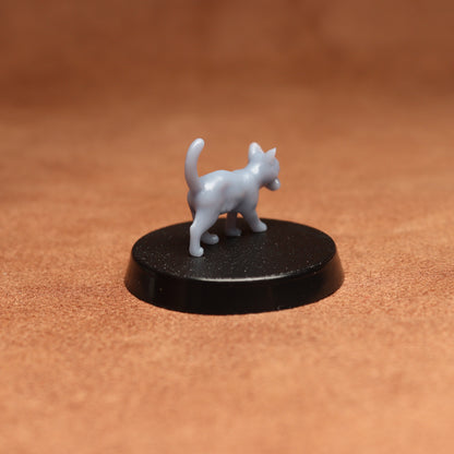 Small white cat figurine on a black base against a brown background