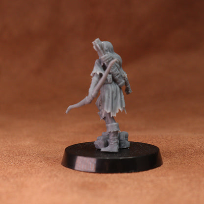A small unpainted gray fantasy tabletop miniature figurine standing on a round black base against a warm brown textured background.