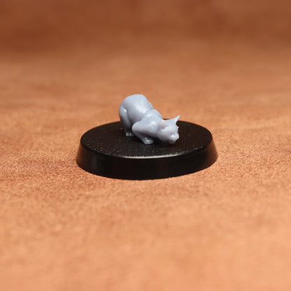 Small gray figurine on a black round base against a brown background