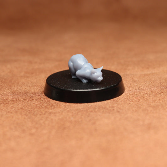 Small gray figurine on a black round base against a brown background