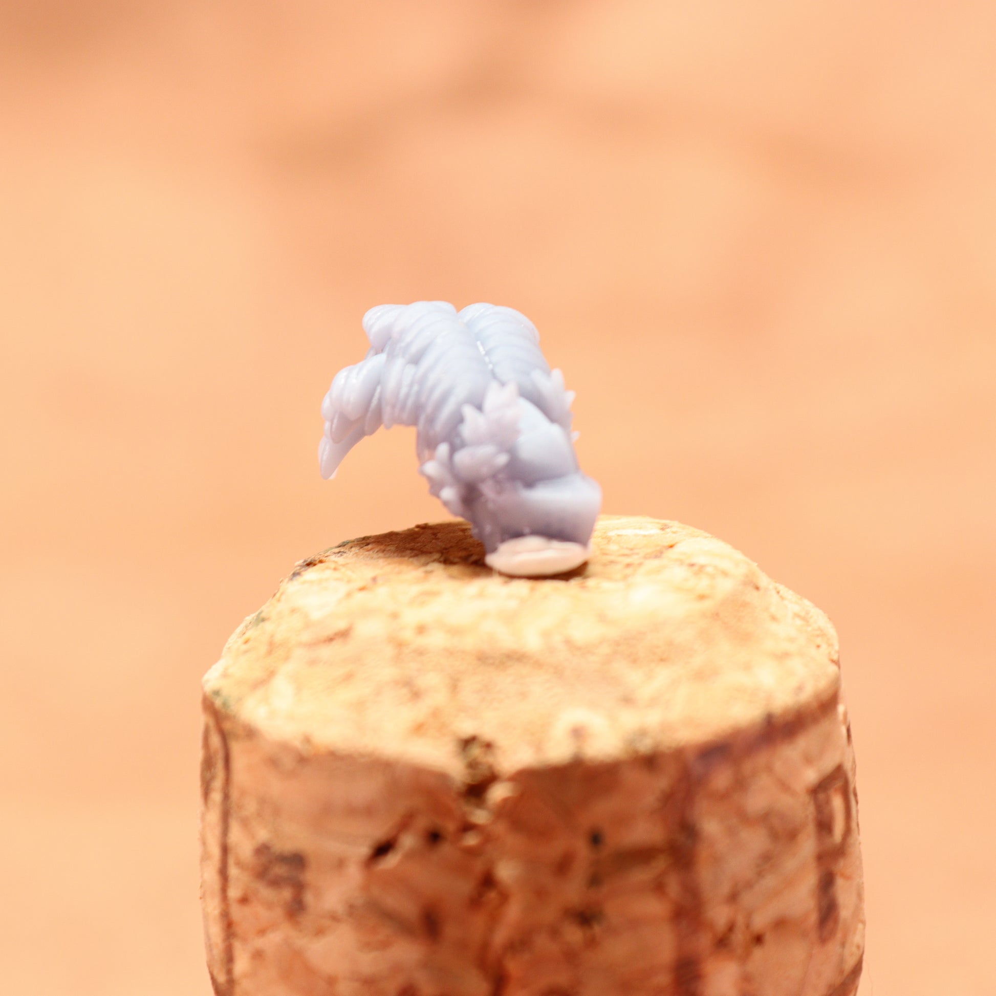 Small figurine of a cloud on top of a cork with a blurred orange background