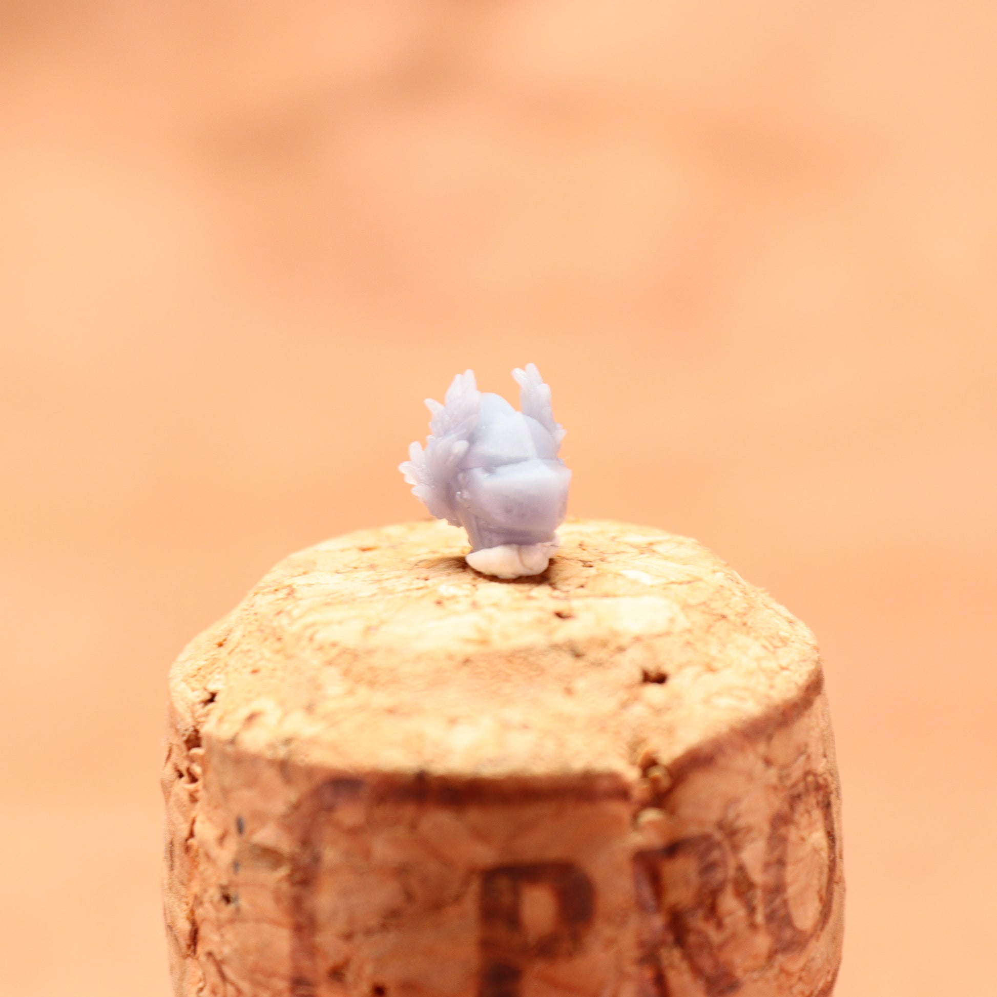 Small white figurine on a cork with a blurred orange background
