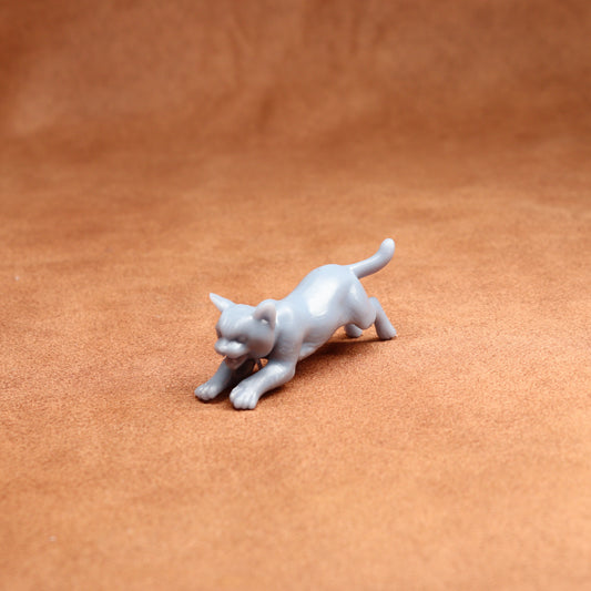 grey resin miniature cat figure on a brown surface
