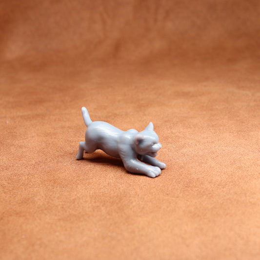 grey resin miniature cat figure on a brown surface