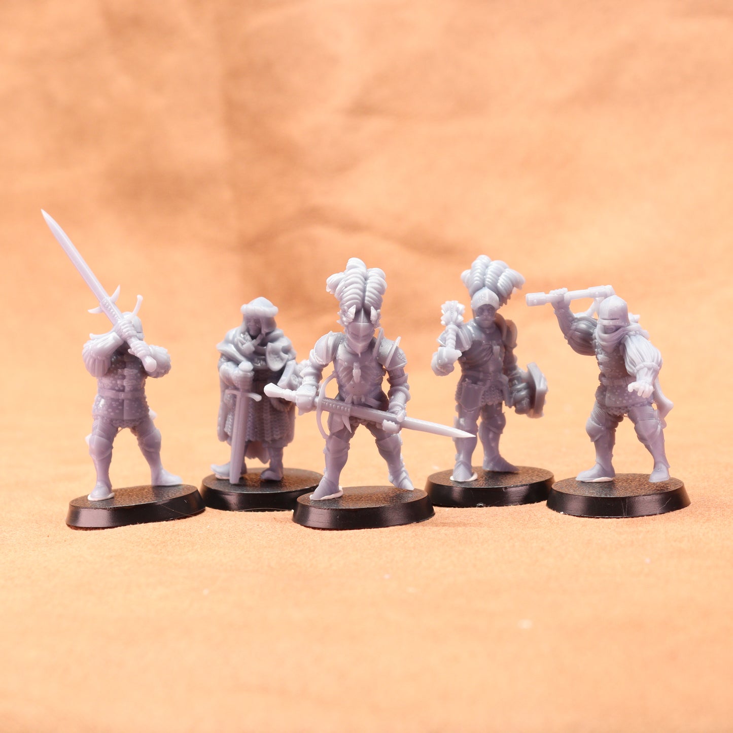 Five white miniature figures on black bases against an orange background