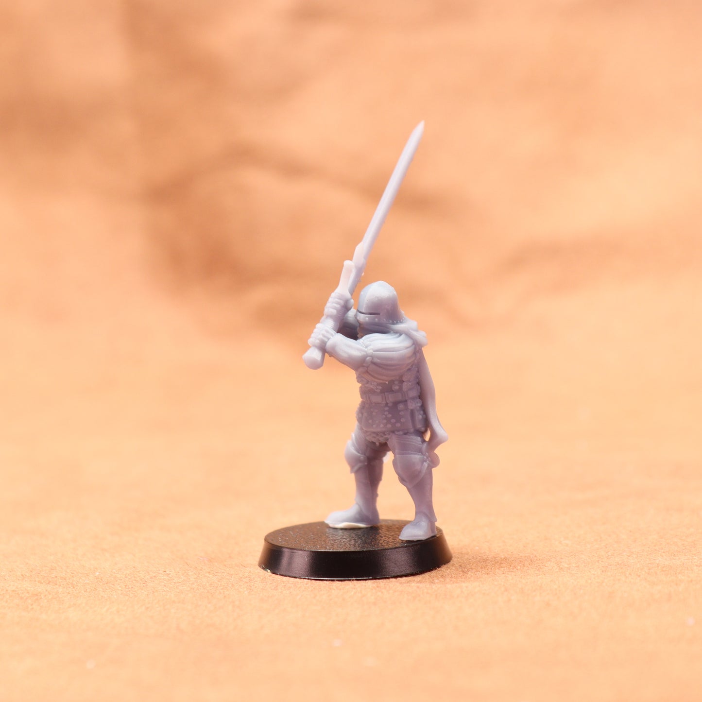White miniature figurine of a warrior holding a spear on an orange background