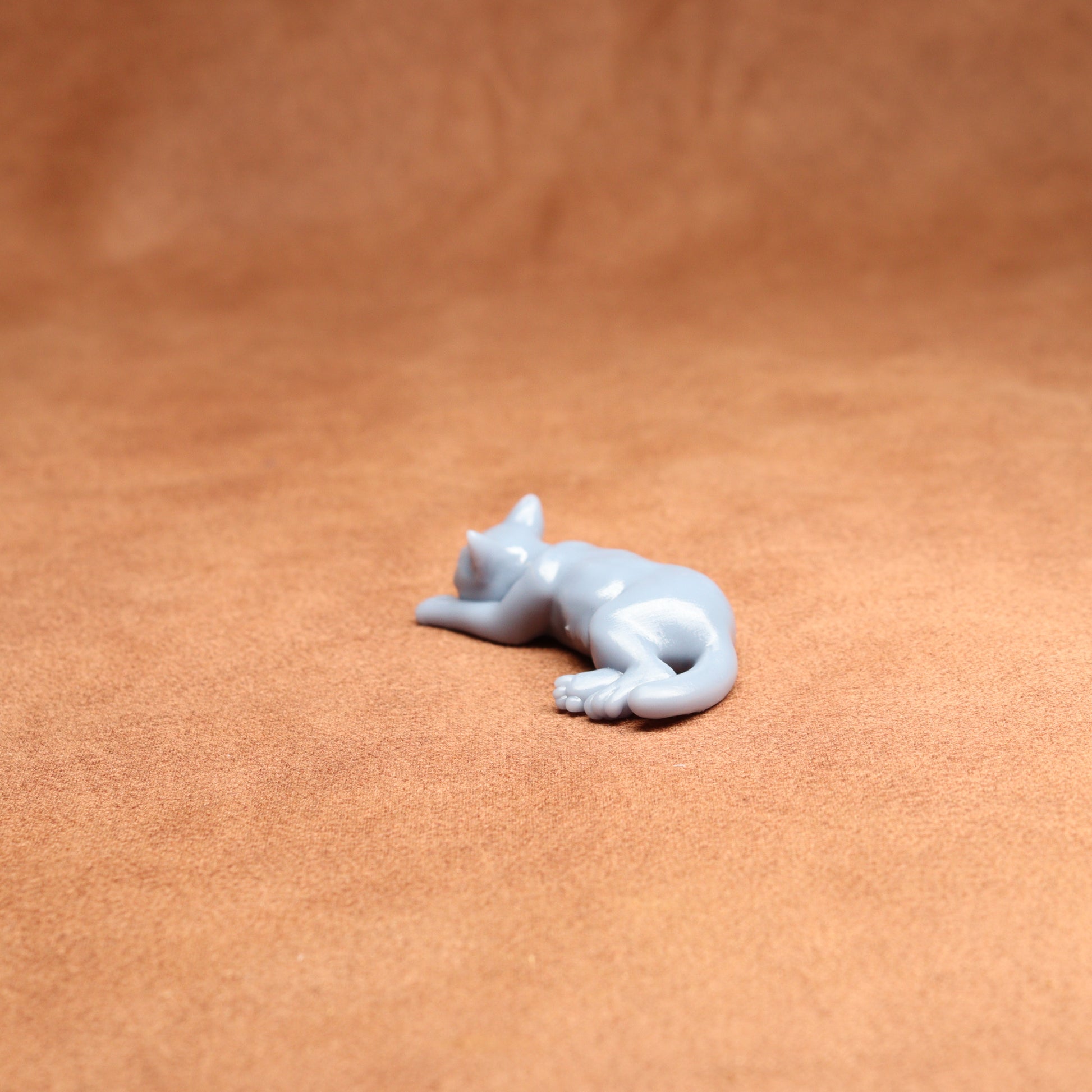 White resin cat figurine on a brown leather surface