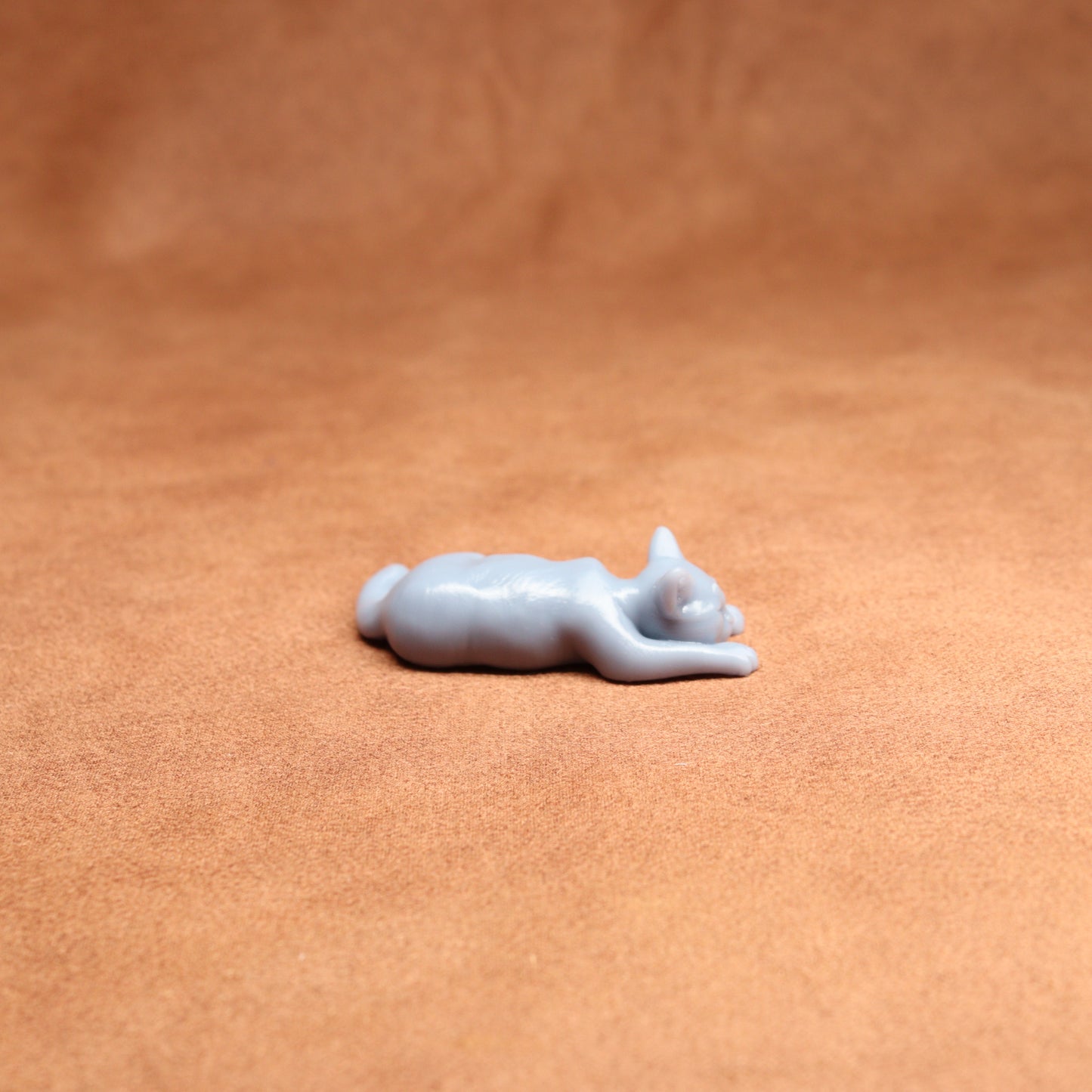 White cat figurine on a brown leather surface