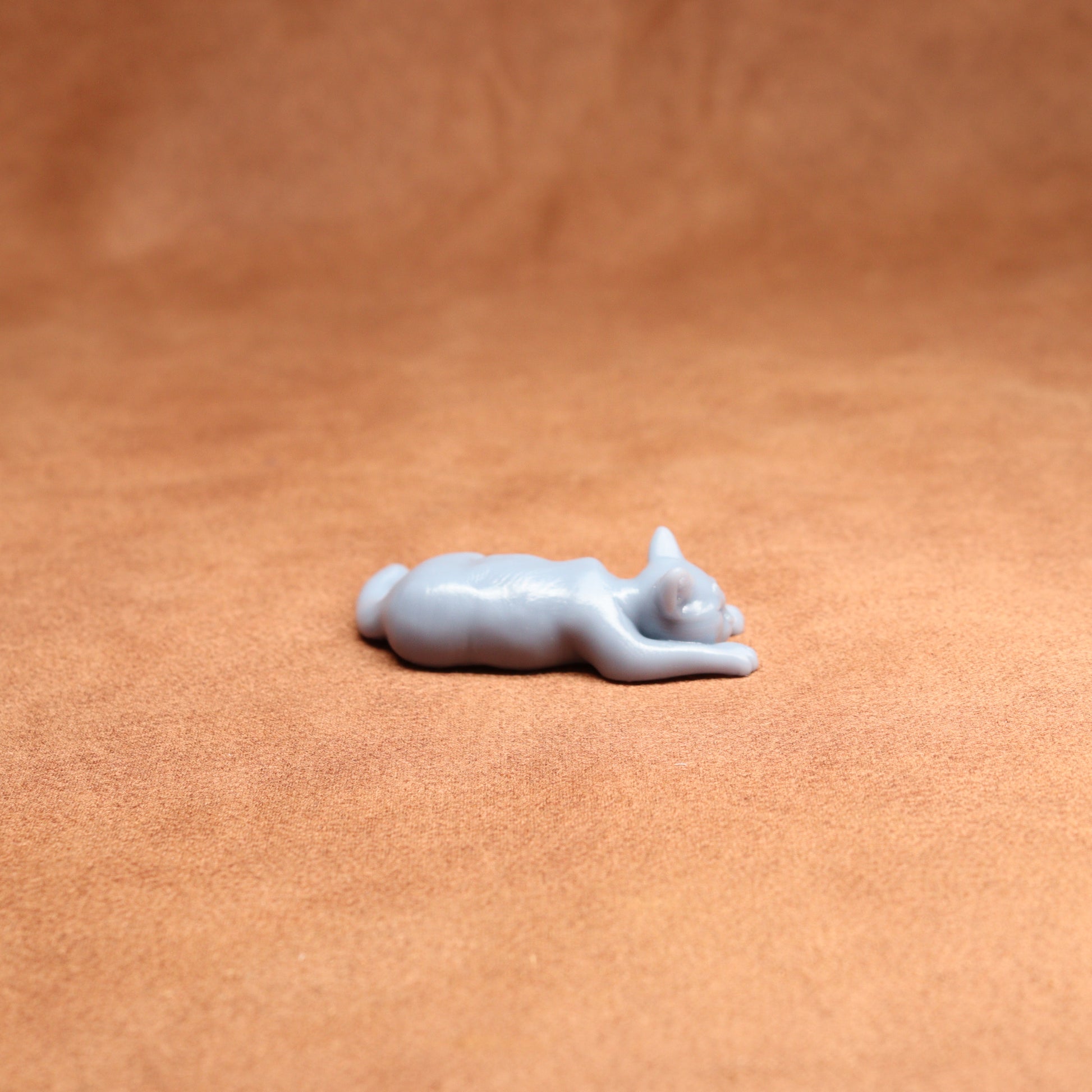 White cat figurine on a brown leather surface