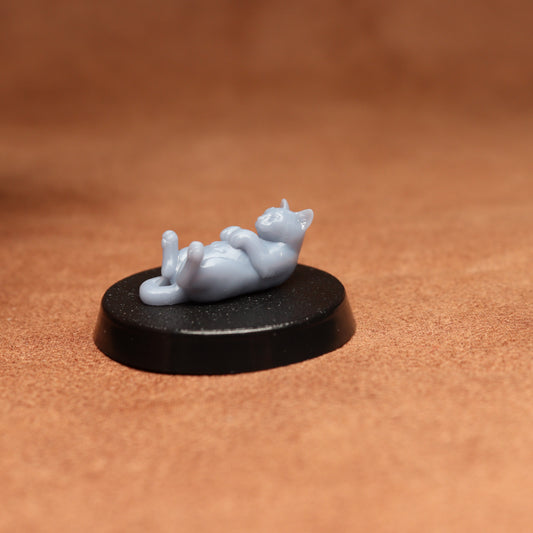 grey cat resin miniature on a black base on a brown background.