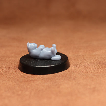 grey cat resin miniature on a black base on a brown background.