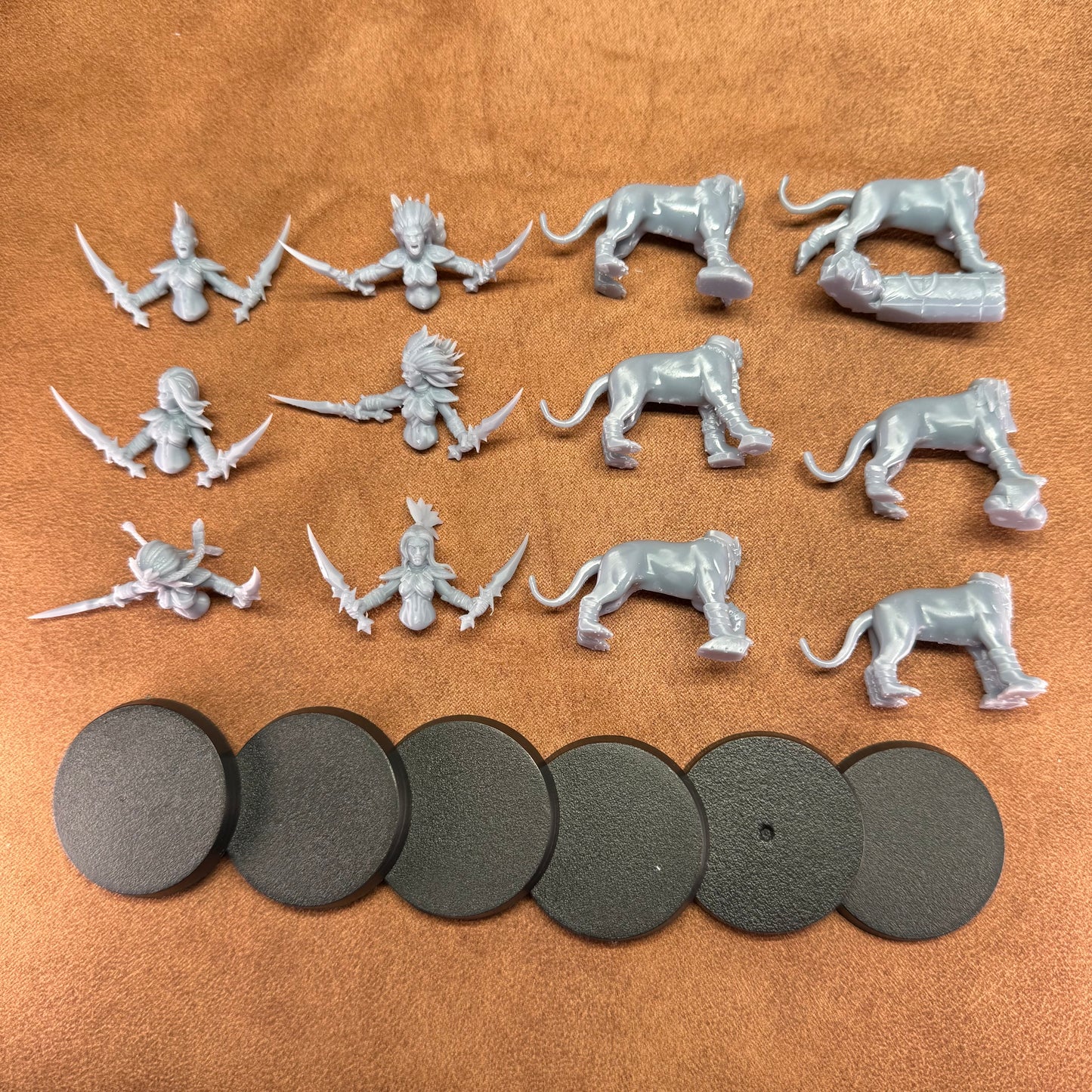 Collection of gray miniature figures and round bases on a brown surface