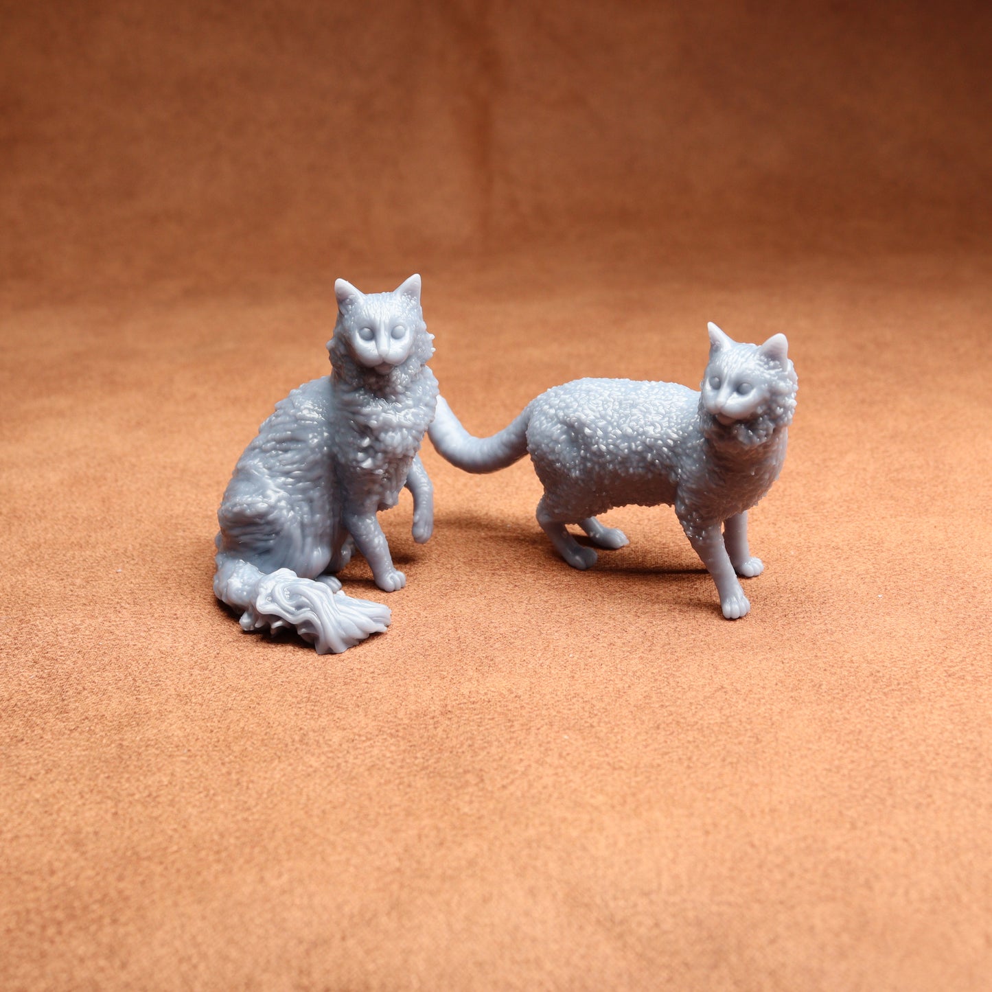 Two gray cat figurines on a brown surface