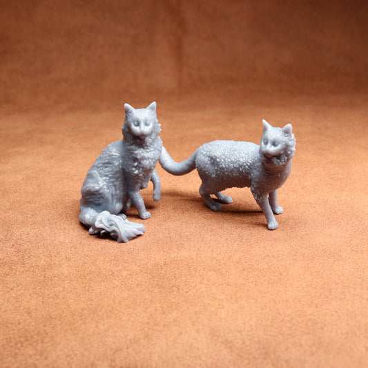 Two gray cat figurines on a brown surface