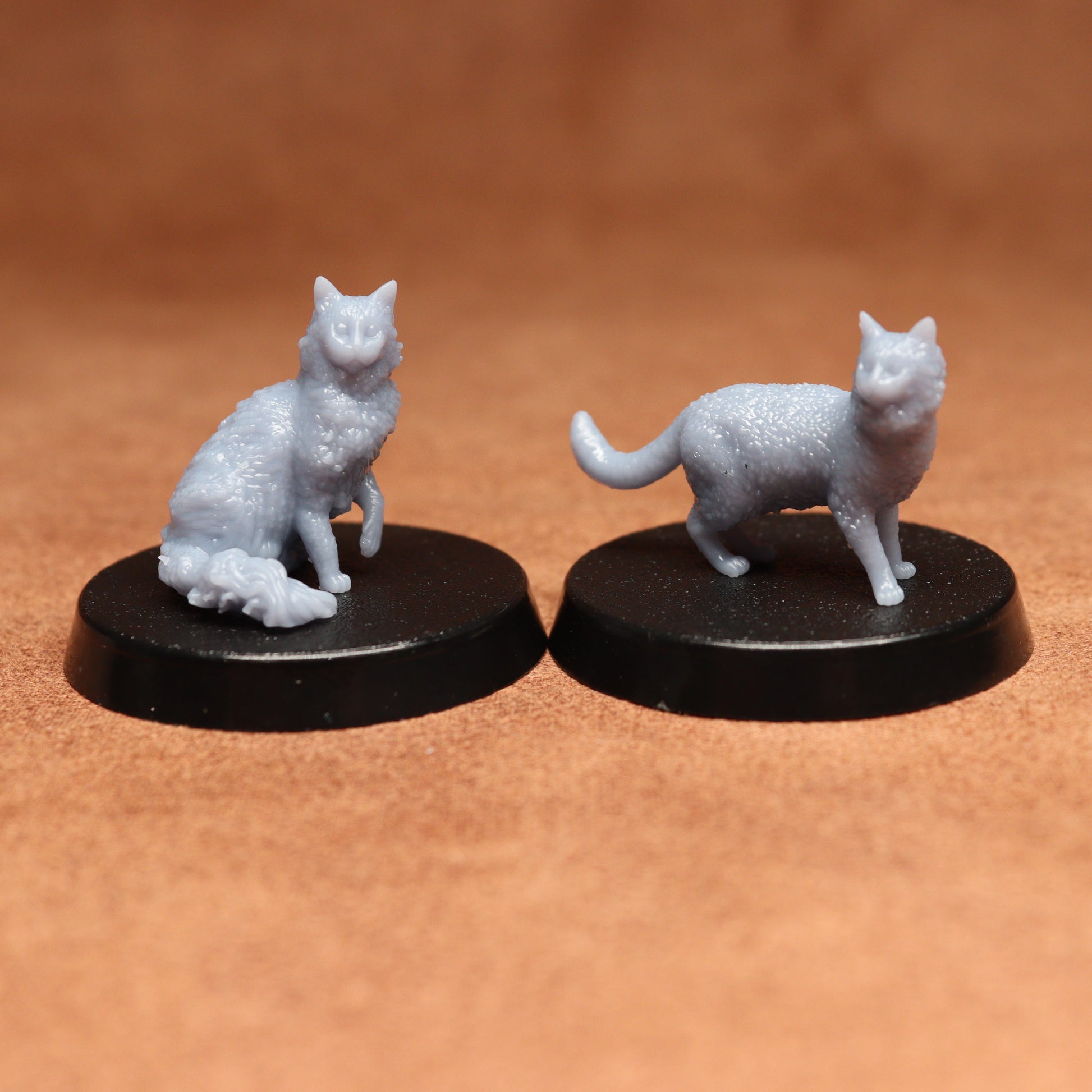 Two white cat figurines on black bases against a brown background
