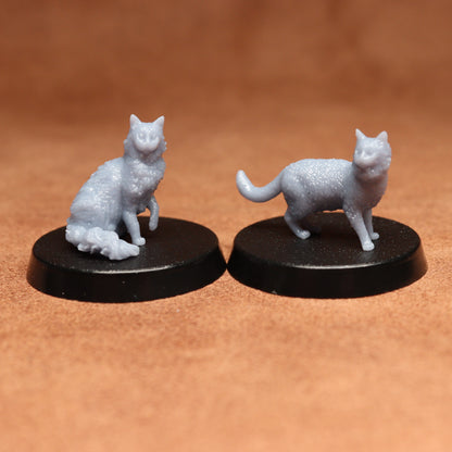 Two white cat figurines on black bases against a brown background