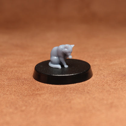 grey cat resin miniature on a black base on a brown background.