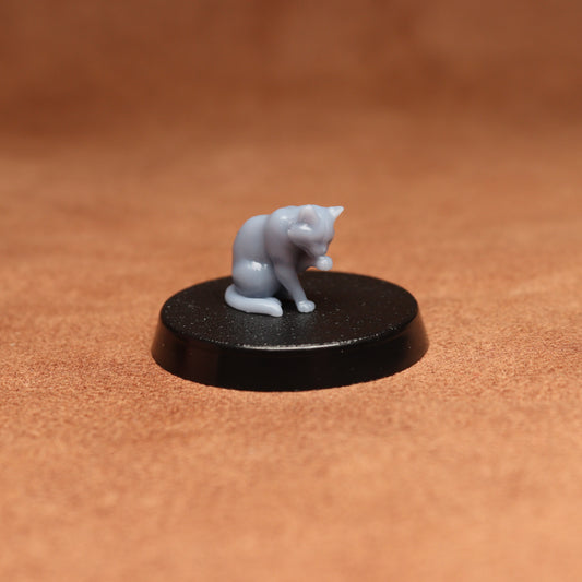 grey cat resin miniature on a black base on a brown background.
