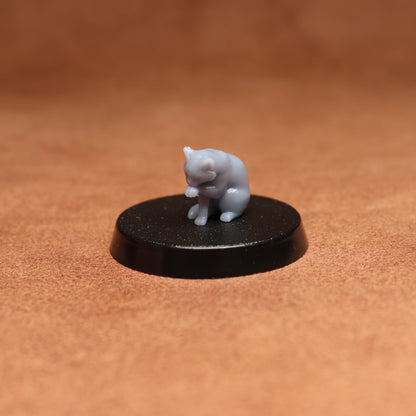 grey cat resin miniature on a black base on a brown background.