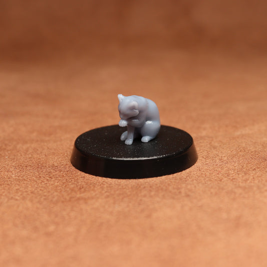 grey cat resin miniature on a black base on a brown background.