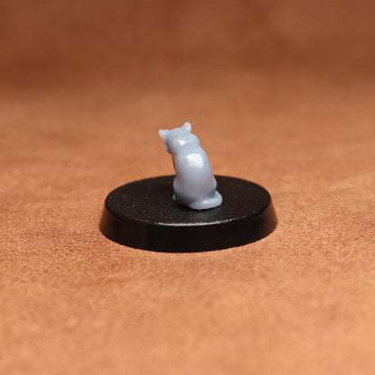 grey cat resin miniature on a black base on a brown background.