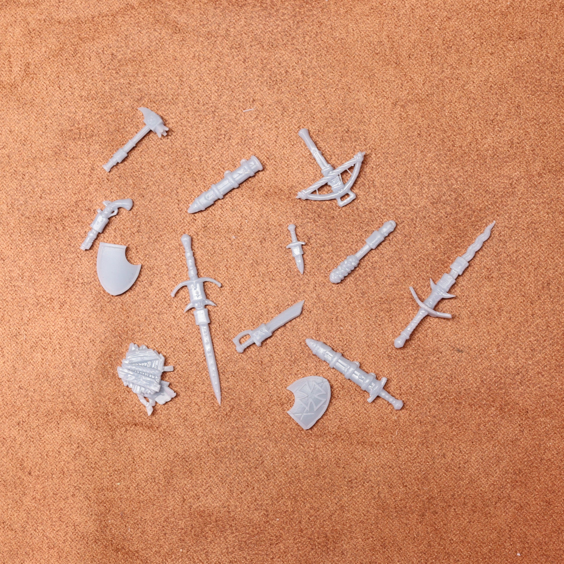 Set of white plastic weapon and armor pieces on a brown surface