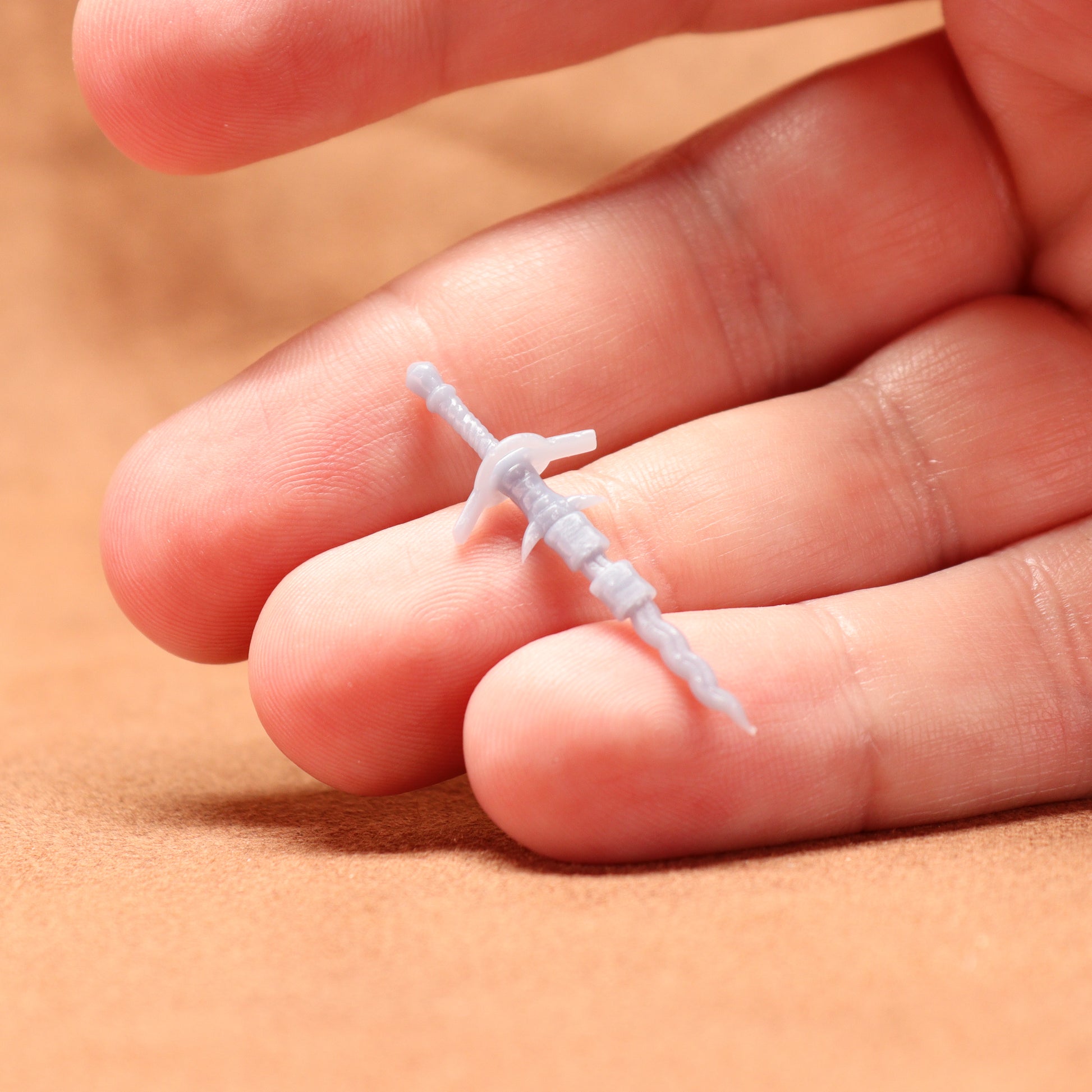 Small plastic tool on a person's finger against a beige background