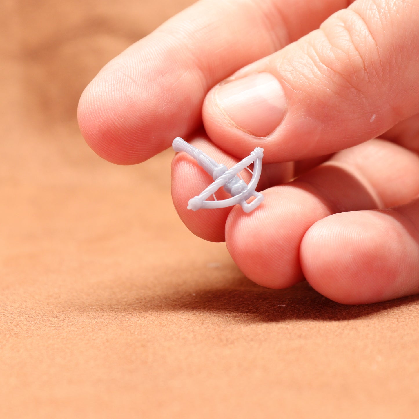 Small white object held between fingers on a beige background