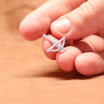 Small white object held between fingers on a beige background