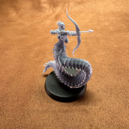 Miniature figurine of a dragon-like creature with a humanoid figure on a brown surface