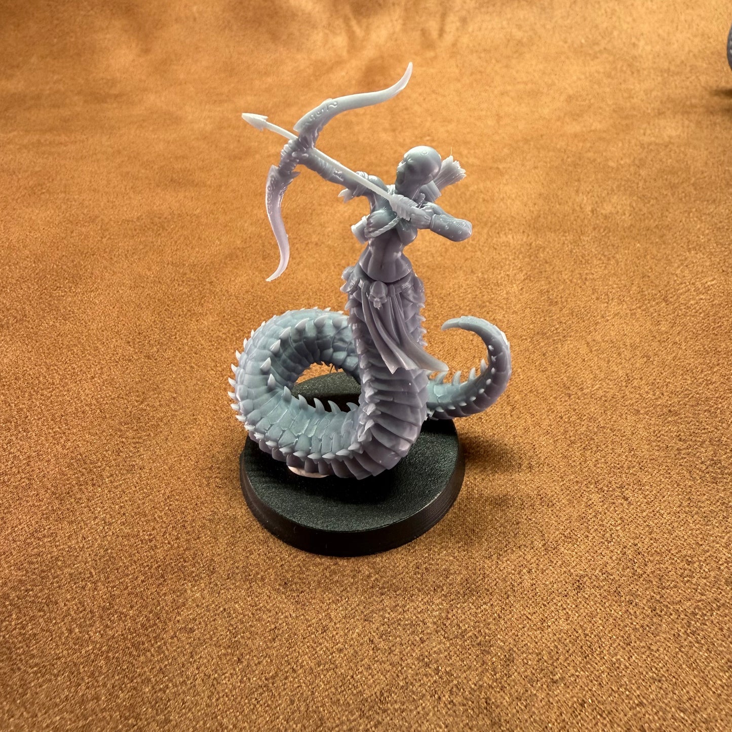 Miniature figurine of a creature with a bow on a brown surface