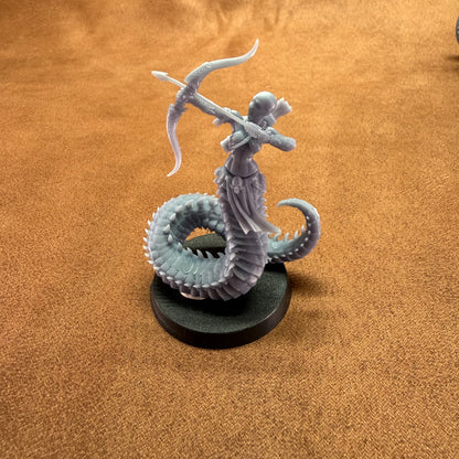 Miniature figurine of a creature with a bow on a brown surface