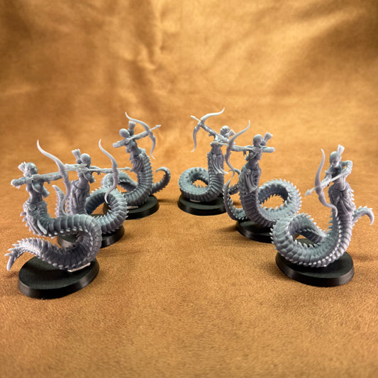 Four dragon-like figurines on black bases against a brown fabric background