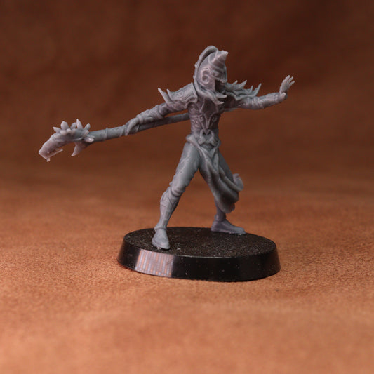 A gray unpainted fantasy miniature figurine of a warrior holding a long sword, standing on a round black base against a warm brown textured background.