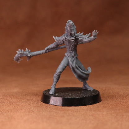 A gray unpainted fantasy miniature figurine of a warrior holding a spiked mace, standing on a round black base against a warm brown background.