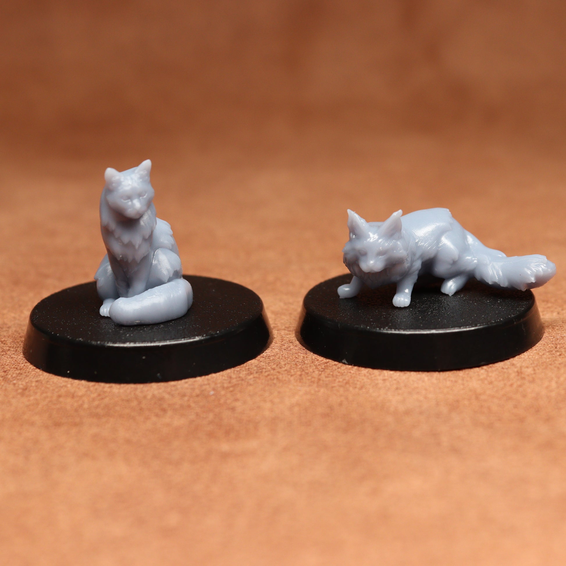 Two white cat figurines on black bases against a brown background