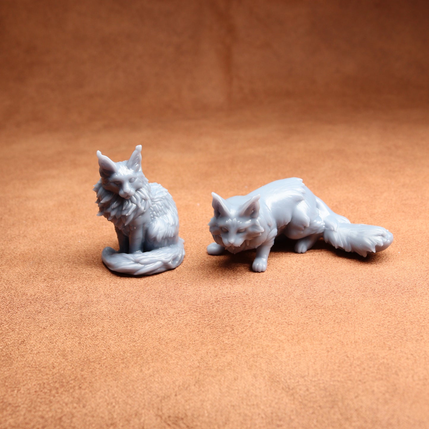Two gray ceramic fox figurines on a brown surface